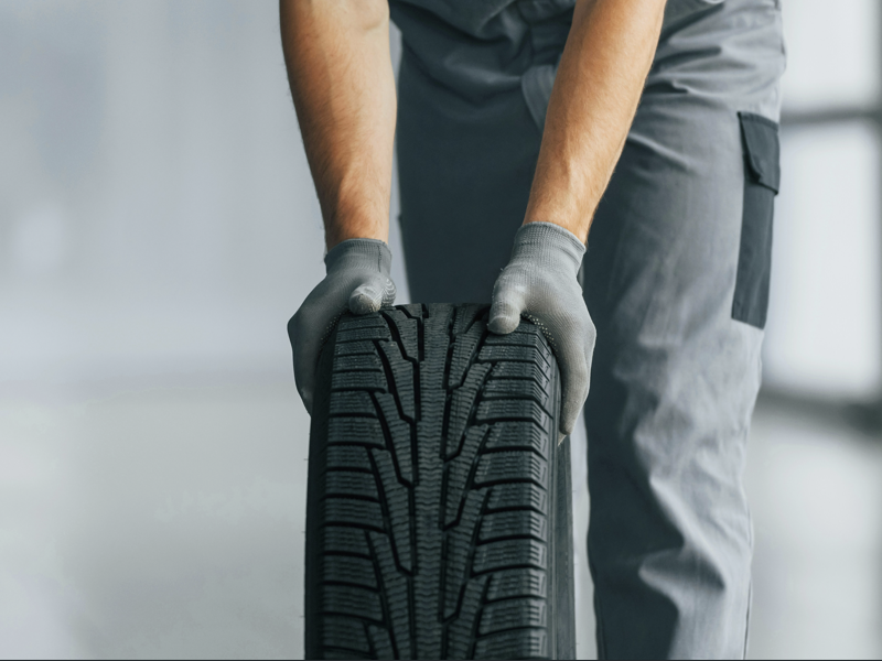 Technician holding tire during wheel alignment service